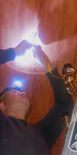 Un hombre que tiene una linterna de cabeza sostiene unos cables que salen de un techo