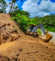Miniatura de retroexcavadora al lado de una zona excavada para alcantarilla.