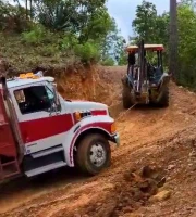 miniatura de una retroexcavadora tirando de un camión, en una cuesta